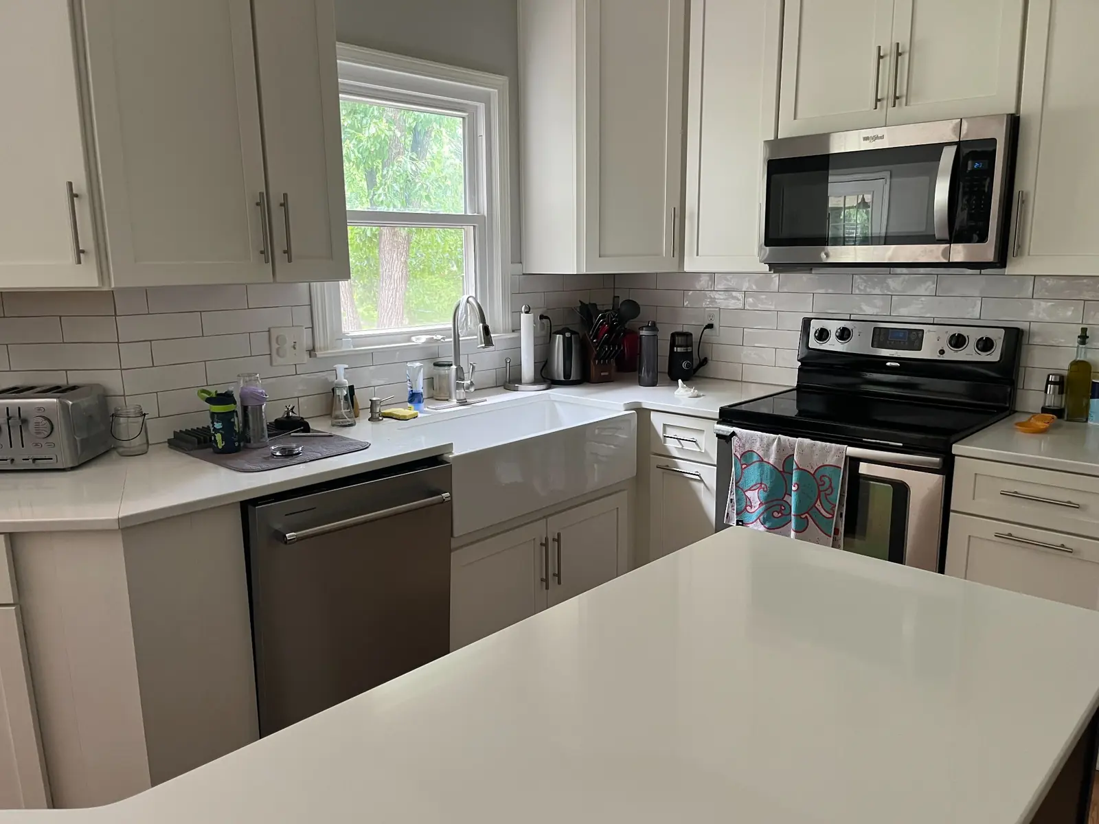 Kitchen with farmhouse sink, white cabinets, and an island — before