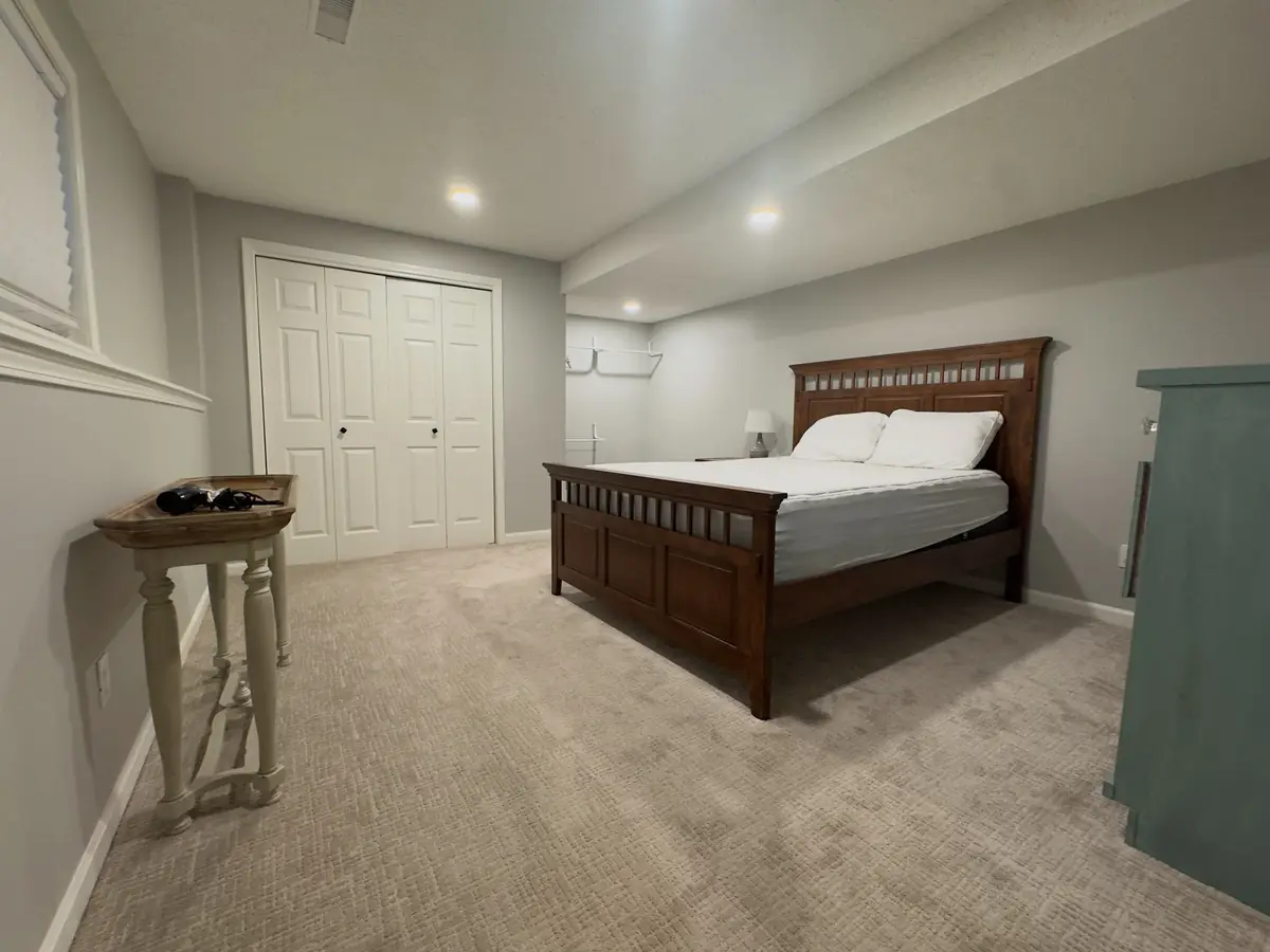 Basement bedroom with wooden bedframe — before